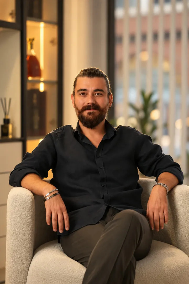 Dr. Erdem Çalışkan klinikte siyah gömleğiyle otururken